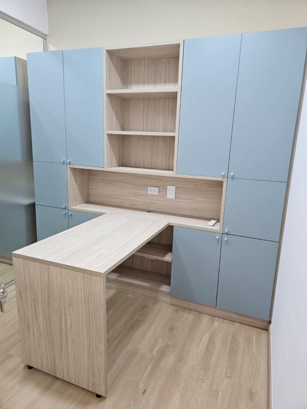 Small office with built-in blue cabinetry and wooden floor inside medical tower