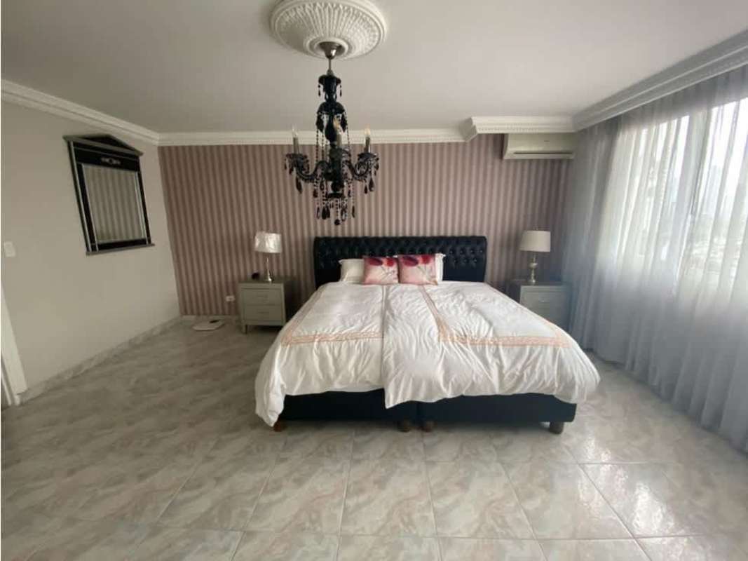 Modern bedroom with striped accent wall, chandelier and large window PH Ritz Punta Paitilla