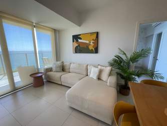 Living area with large windows opening to balcony and Pacific Ocean at PH Solaria Punta Caelo