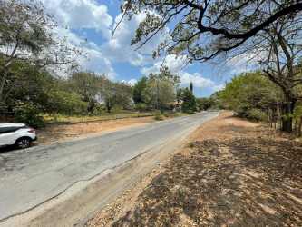 Rural road access to large vacant land with parked car and trees in San Carlos Panama