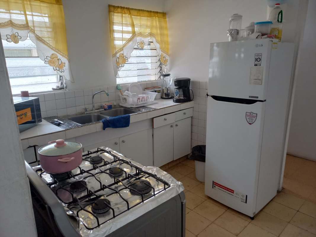 Simple kitchen double sink refrigerator gas stove microwave floral curtain Obarrio room rental Panama.
