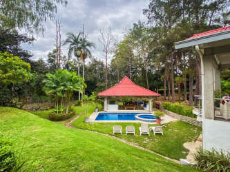 Large tropical garden swimming pool red roof gazebo sun loungers lush greenery Santa Clara Panama villa