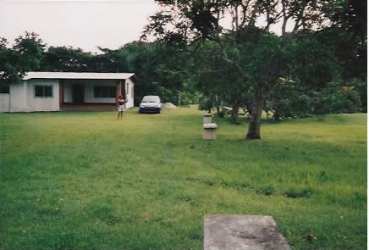 Single-story beach house with large grassy lawn and tropical landscape