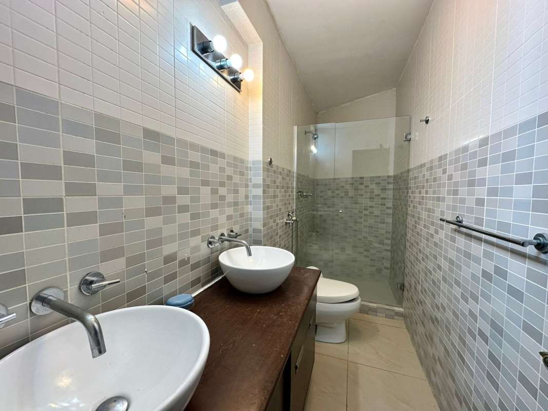 Bathroom with dual vessel sinks, mosaic wall tiles, and glass shower in PH San Francisco Bay Panama