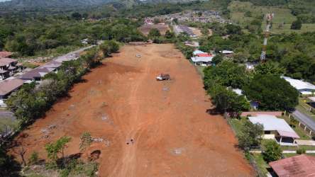 View of large open field for residential project bordered by greenery and existing homes Dolega Panama