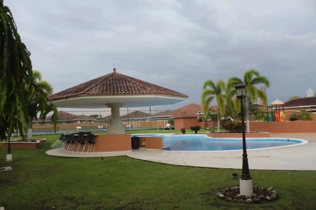 Swimming pool with tiled gazebo bar and tennis courts at Sunset Coast Costa Sur Panama