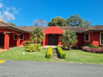 Spanish colonial style beach house with clay tile roof, red façade, lush garden in Coronado