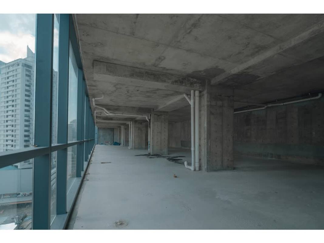 Large open office shell with concrete flooring, floor-to-ceiling windows and city views at PH Nuovo by Armani Casa Panama