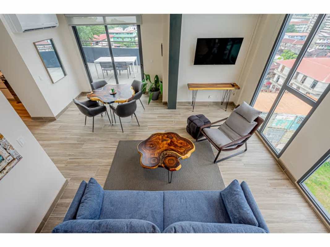 Open plan living room with large windows and steel stairs PH Casco View Casco Viejo Panama