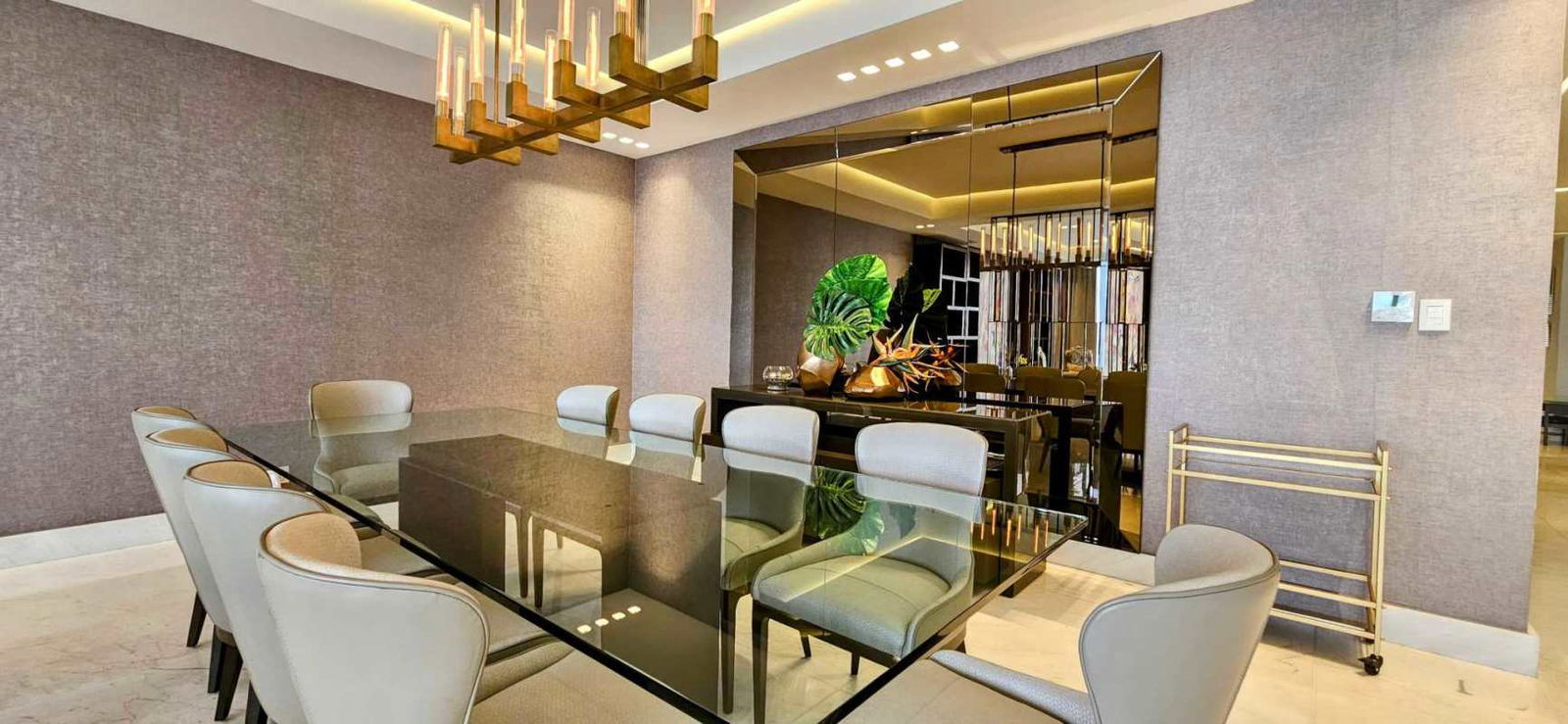 Modern dining room with glass table, chandelier and upholstered chairs at The Residences Punta Pacífica Panama