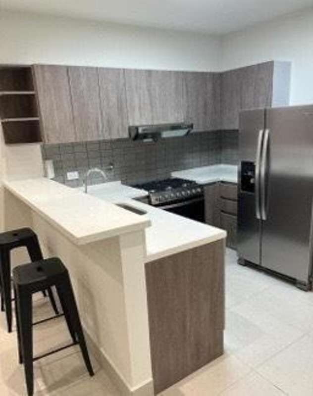 Modern kitchen with appliances, wood cabinetry, breakfast bar PH Coco Place Panama City