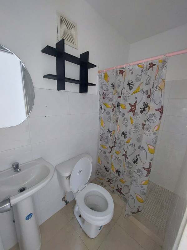 Compact bathroom with pedestal sink, shower curtain, mirror, and black wall shelf in PH Balcones de Santa Fe Pacora Panama