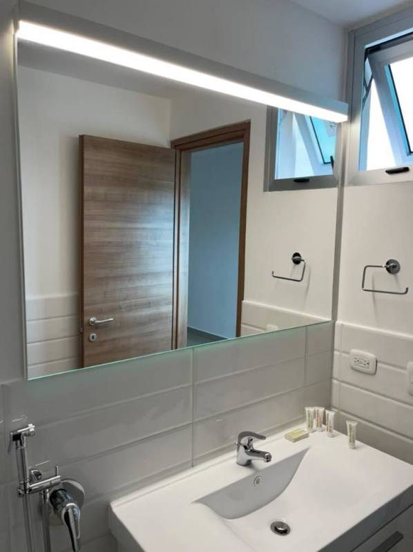 Minimalist bathroom with large mirror, modern fixtures in PH Roma Panama City