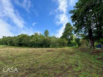 Open grass lot with bordering trees and mountain backdrop in Panama highlands