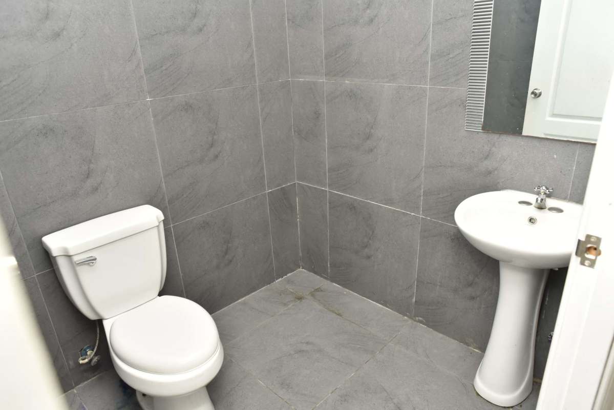 Small bathroom with gray tiles, pedestal sink, mirror and toilet in Plaza San Francisco Panama City