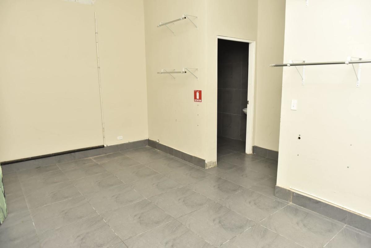 Retail or office unit interior with gray tile flooring, shelving, and a private bathroom door in San Francisco Panama