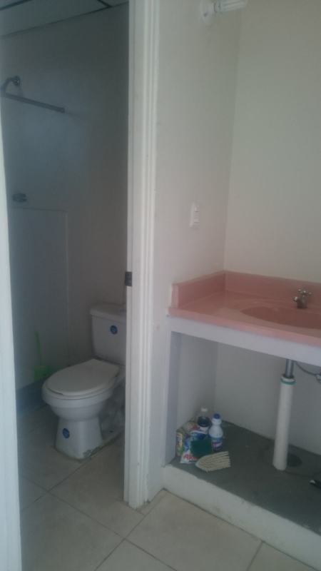 Basic bathroom with tile shower, toilet and pink sink countertop Los Cántaros house Panama