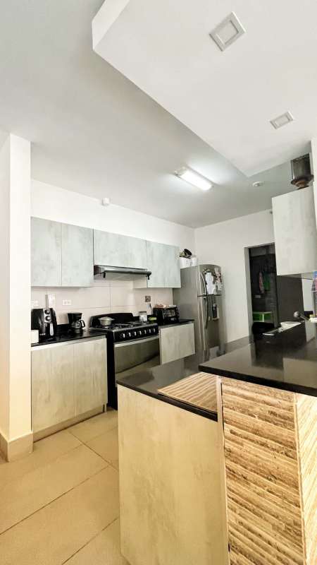 Laundry with stacked appliances, tiled walls in PH La Loma apartment Panama City