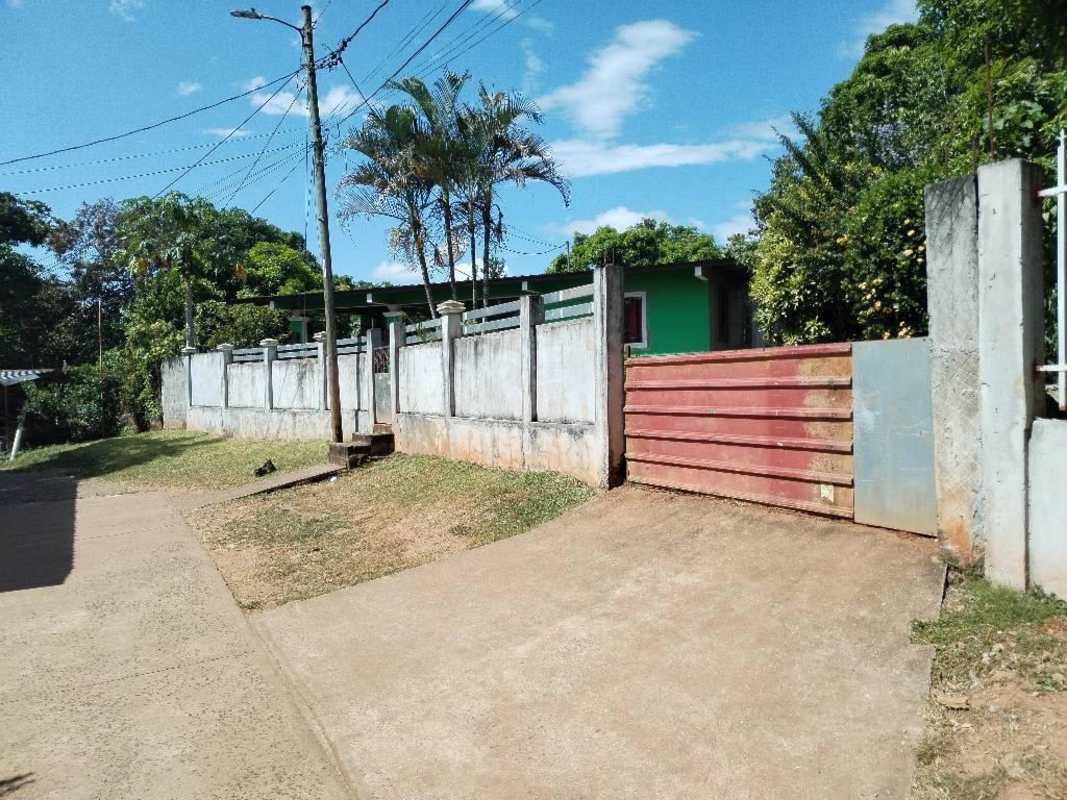 Driveway entrance with metal gate and lush vegetation of affordable house Nueva Esperanza 24 de Diciembre Panama