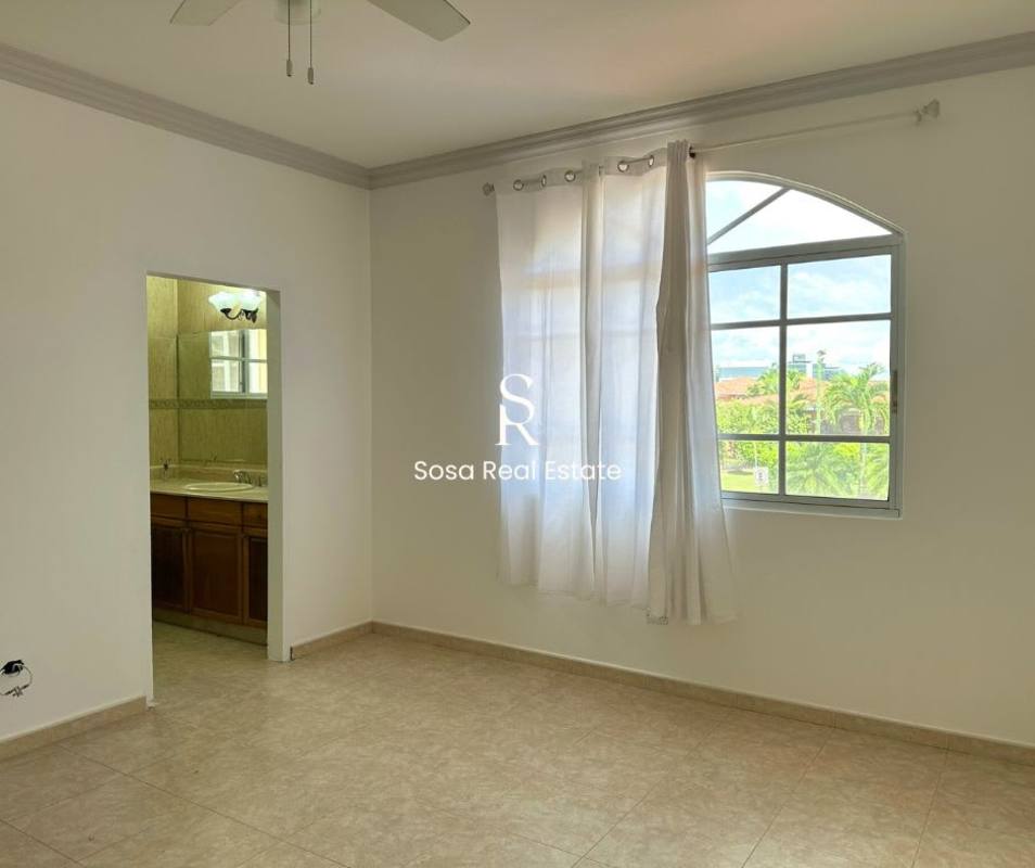 Bedroom with large arched window, fan and ensuite bath in Costa del Este rental home
