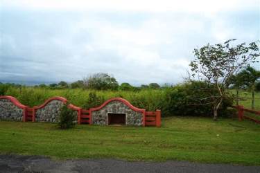 Stone fence with red accent on grass lawn by Las Olas Resort land lot Playa Barqueta Panama