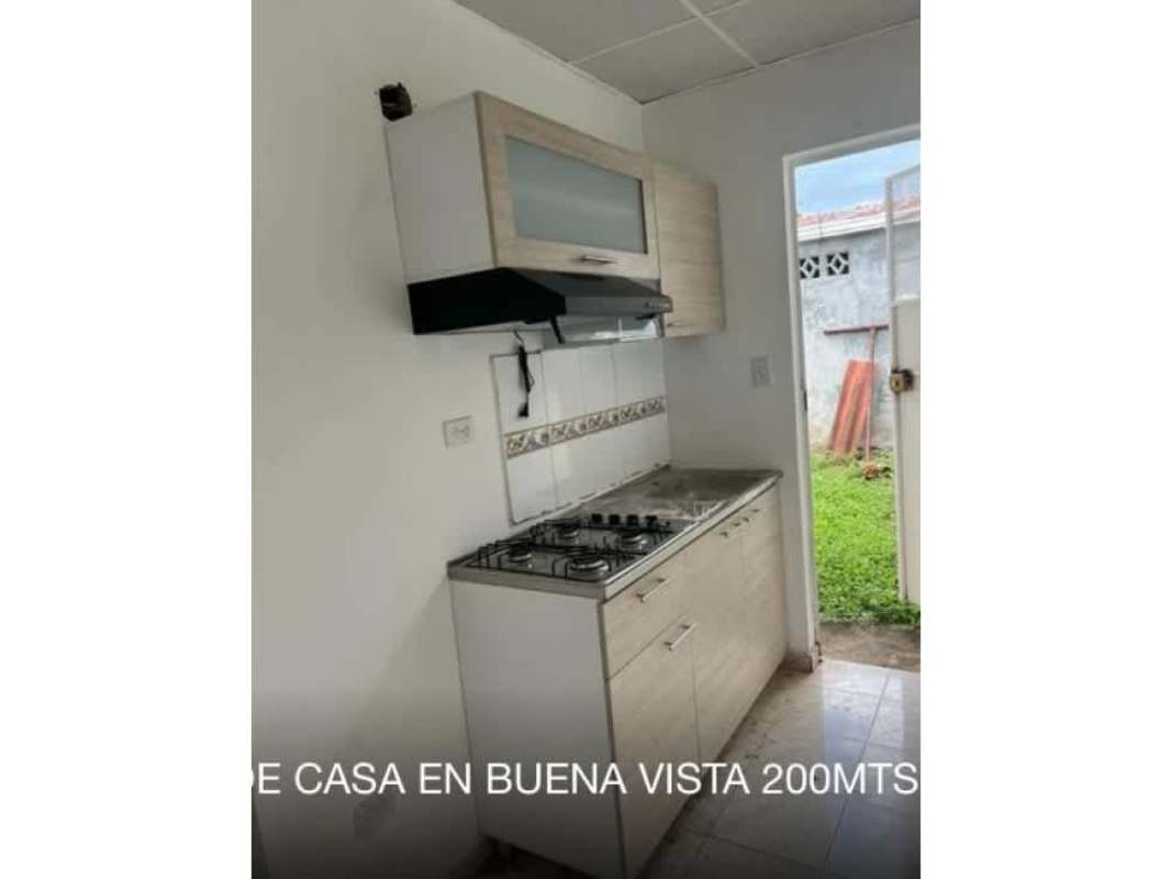 Compact kitchen with tile backsplash, overhead cabinets, stove and door to backyard in BuenaVista II Tocumen Panama