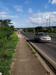 Paved avenue with sidewalk and greenery fronting large land development site in Chitré Panama