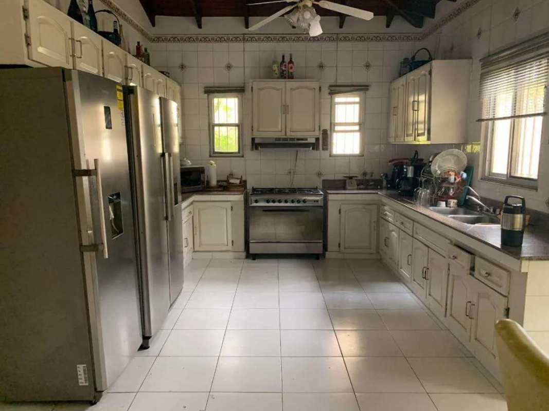 Classic kitchen with white tiles, stainless steel appliances and wood beams Panama City