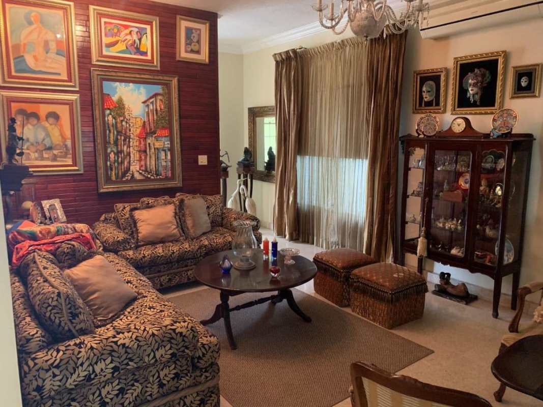 Traditional living room with colorful sofas, wood accent wall and large window Villa de Las Fuentes Panama