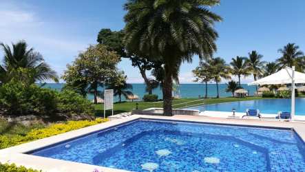 Private white sand beach with palm huts and calm ocean waves at Bijao Beach Club Panama