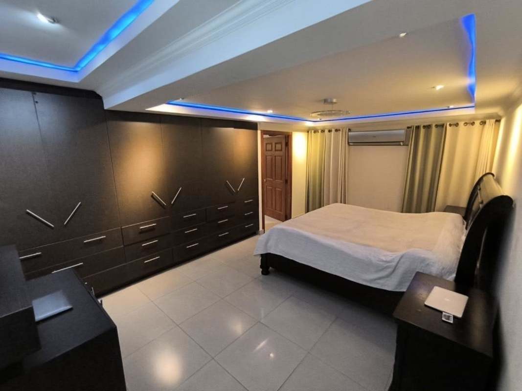 Bedroom with large built-in wardrobes, LED ceiling accents, porcelain floors in Chanis Panama remodeled house