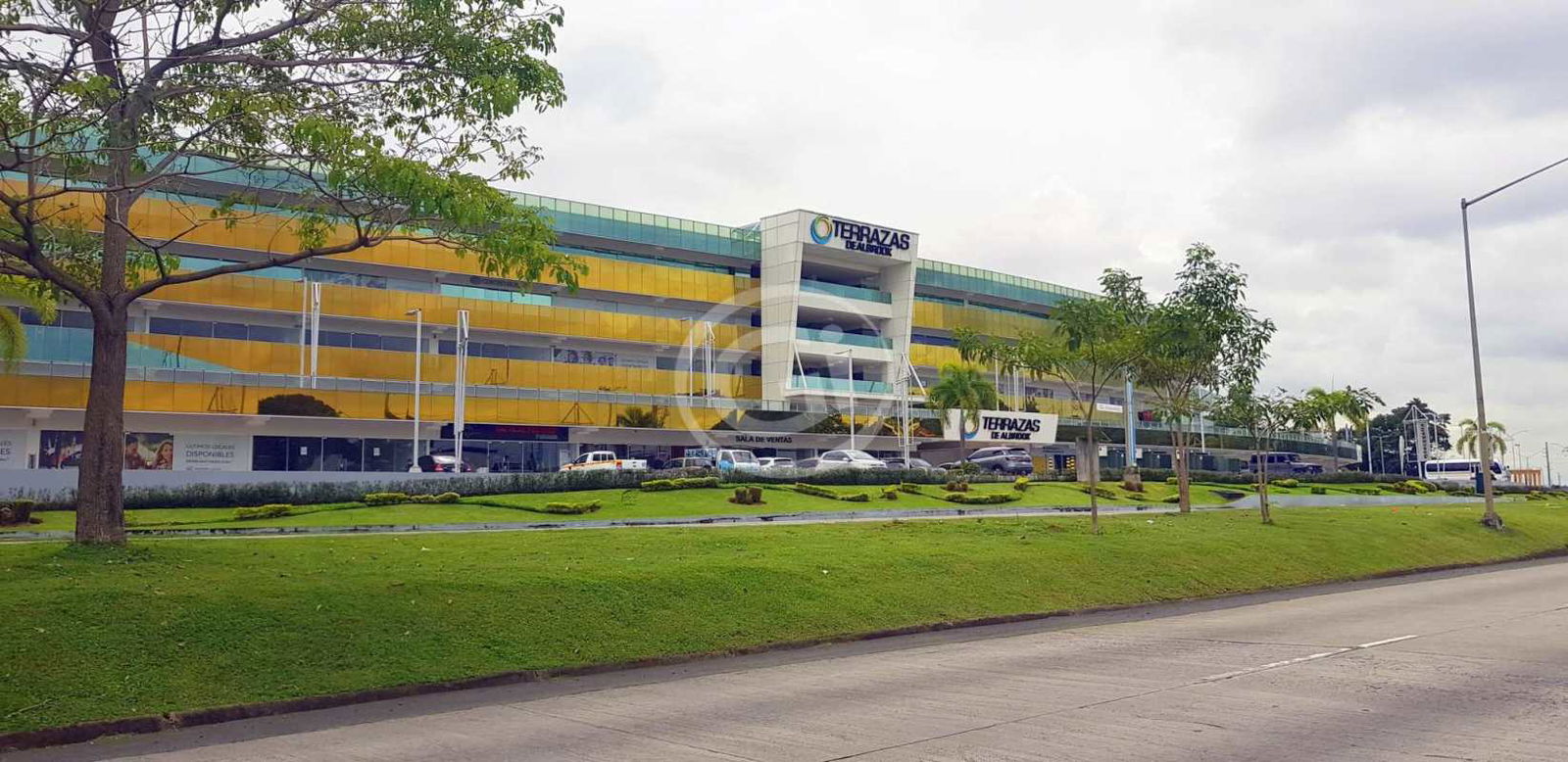 Modern multi-story commercial center with gold tinted reflective glass panels and parking lots in Panama City Albrook
