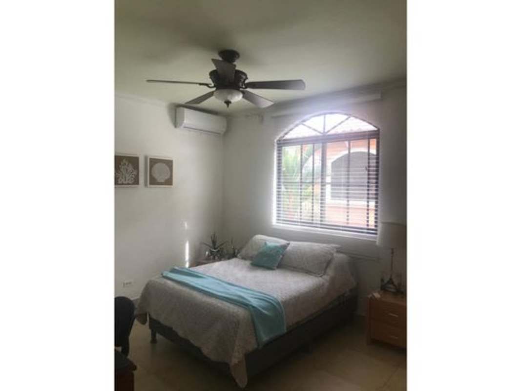 Compact bathroom with oval mirror, black countertop, tiled walls Clayton Village Panama