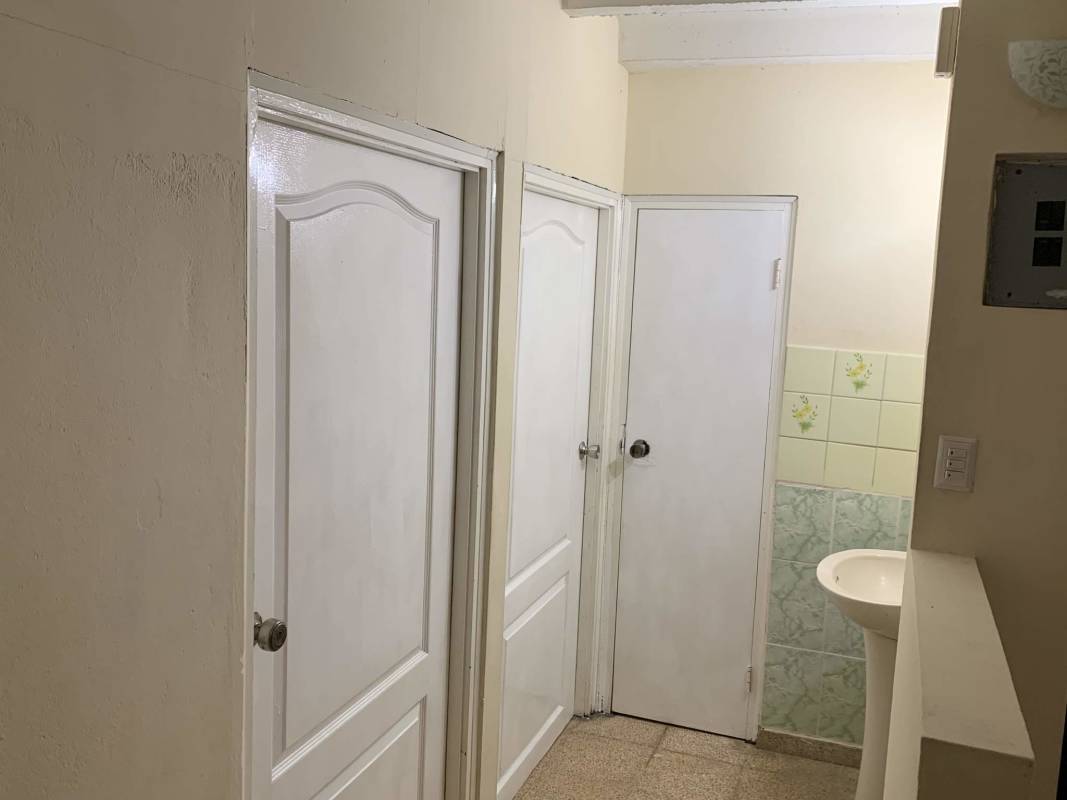 Hallway with tiled wall and doors leading to bathroom in affordable La Loceria apartment Panama