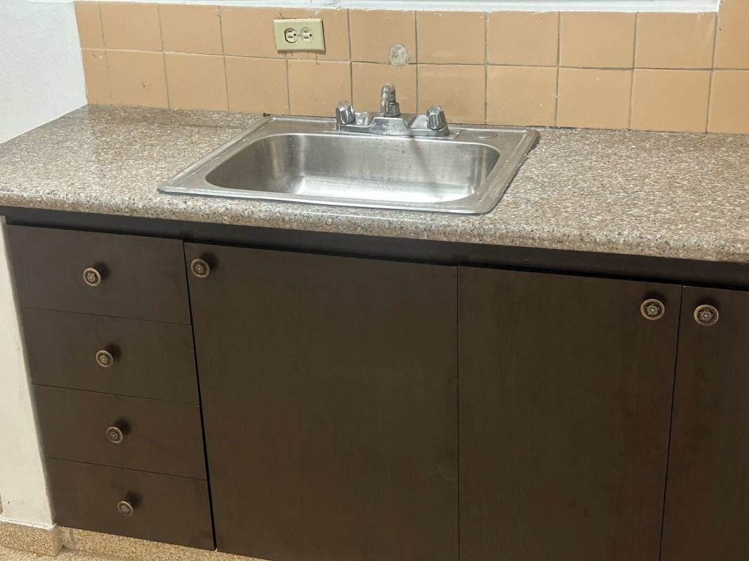 Compact kitchen with granite-style counter and dark cabinetry La Loceria Panama apartment