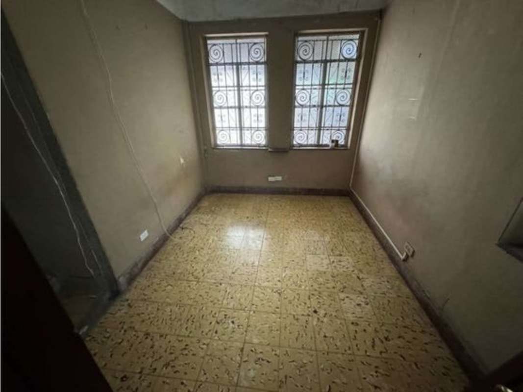 Bright living room with tiled floor, barred windows, ceiling fans in corner house Avenida Balboa Panama