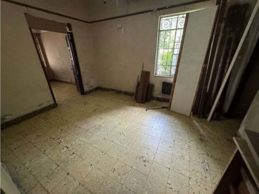 Spacious empty room with tiled floors, window grilles, and renovation potential near Balboa City Panama