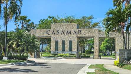 Resort pool facing ocean with lounge chairs and palm trees Casamar Panama