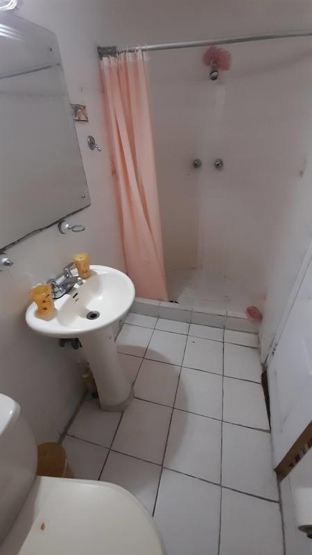 Simple bathroom with pedestal sink, tiles, mirror in apartment near Calle 50 Panama