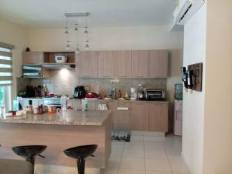 Spacious kitchen with granite island and wooden cabinets in Bijao beach villa Panama