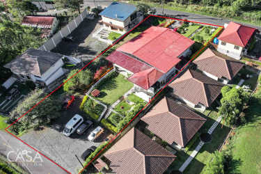 Aerial shot complex buildings with red roofs, gardens, and Boquete mountains Panama