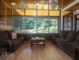 Living room with wood paneling, modern sofas, and garden views in Hotel Central Boquete Panama