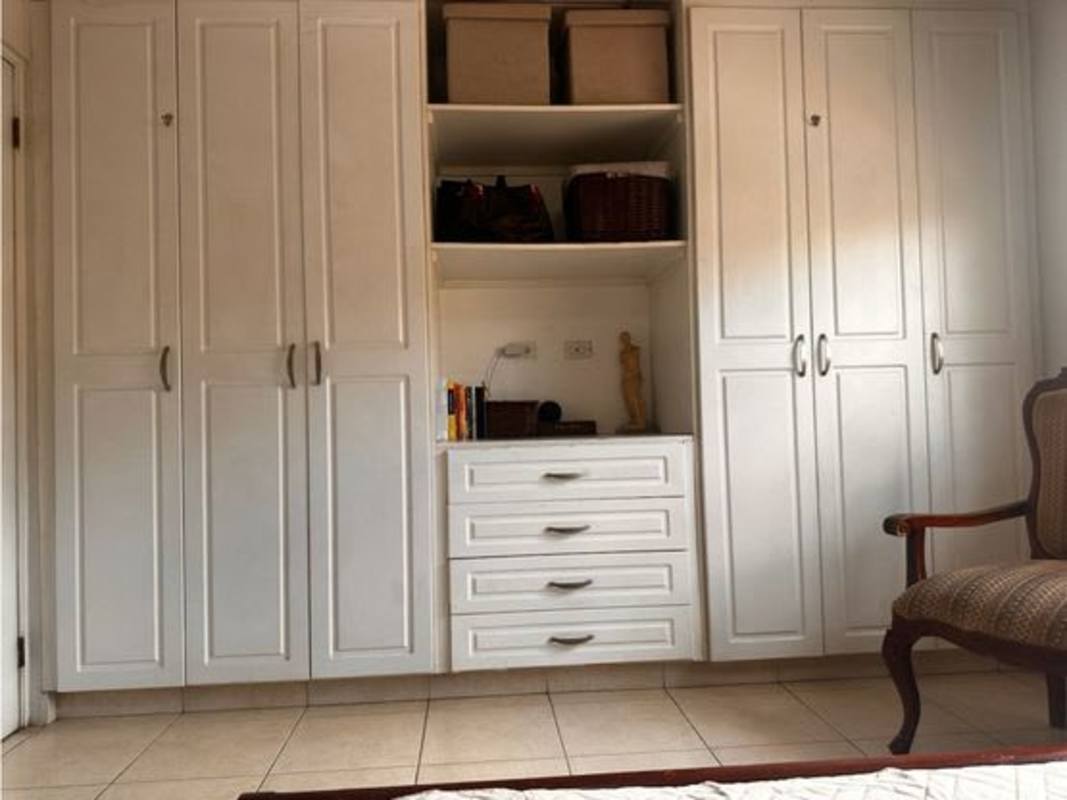 Traditional master bedroom with ceiling fan AC wooden bed tile floors armchair closet Dorado Lakes Panama