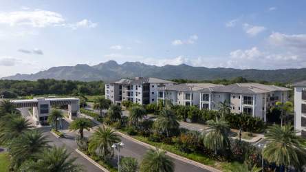 Aerial view of modern gated beachfront community Playa Caracol with mountain backdrop in Panama.