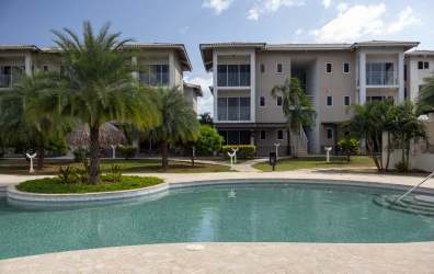 Palm trees, blue sun loungers, white sand beach and ocean surf at Playa Caracol Panama.
