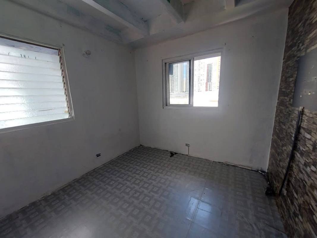 Interior space with stone accent wall, ceiling beams and tile floor in apartment Villa de las Fuentes Panama