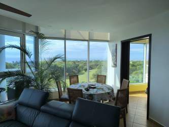 Bright living dining space with balcony access and Pacific Ocean views in Coronado Golf apartment Panama