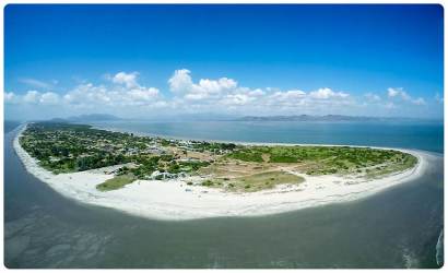 Aerial island view of coastal beachfront land with sandy beach and mountains at Punta Chame Panama