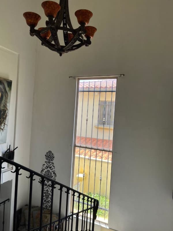 Interior stairwell with ornate iron railing large window natural light chandelier in Paseo Dorado Dorado Lake house