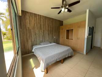 Bedroom featuring wood accent wall, tile flooring garden view Playa Blanca Resort condo Río Hato Panama